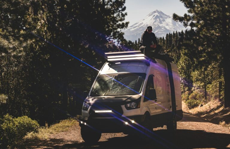 Home 6 A man sitting on top of a van on a dirt road