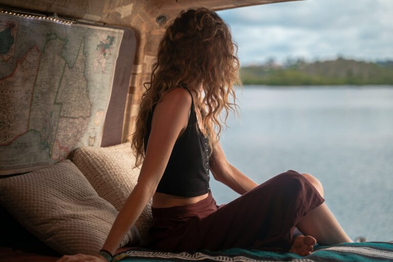 Home 15 Woman wearing black spaghetti strap top sitting viewing body of water